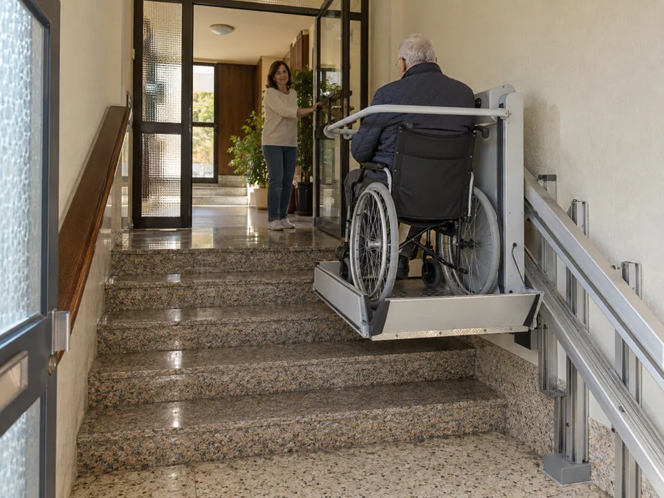 Salvaescaleras para comunidades de vecinos en Alcobendas: vecino en silla de ruedas subiendo los escalones del portal